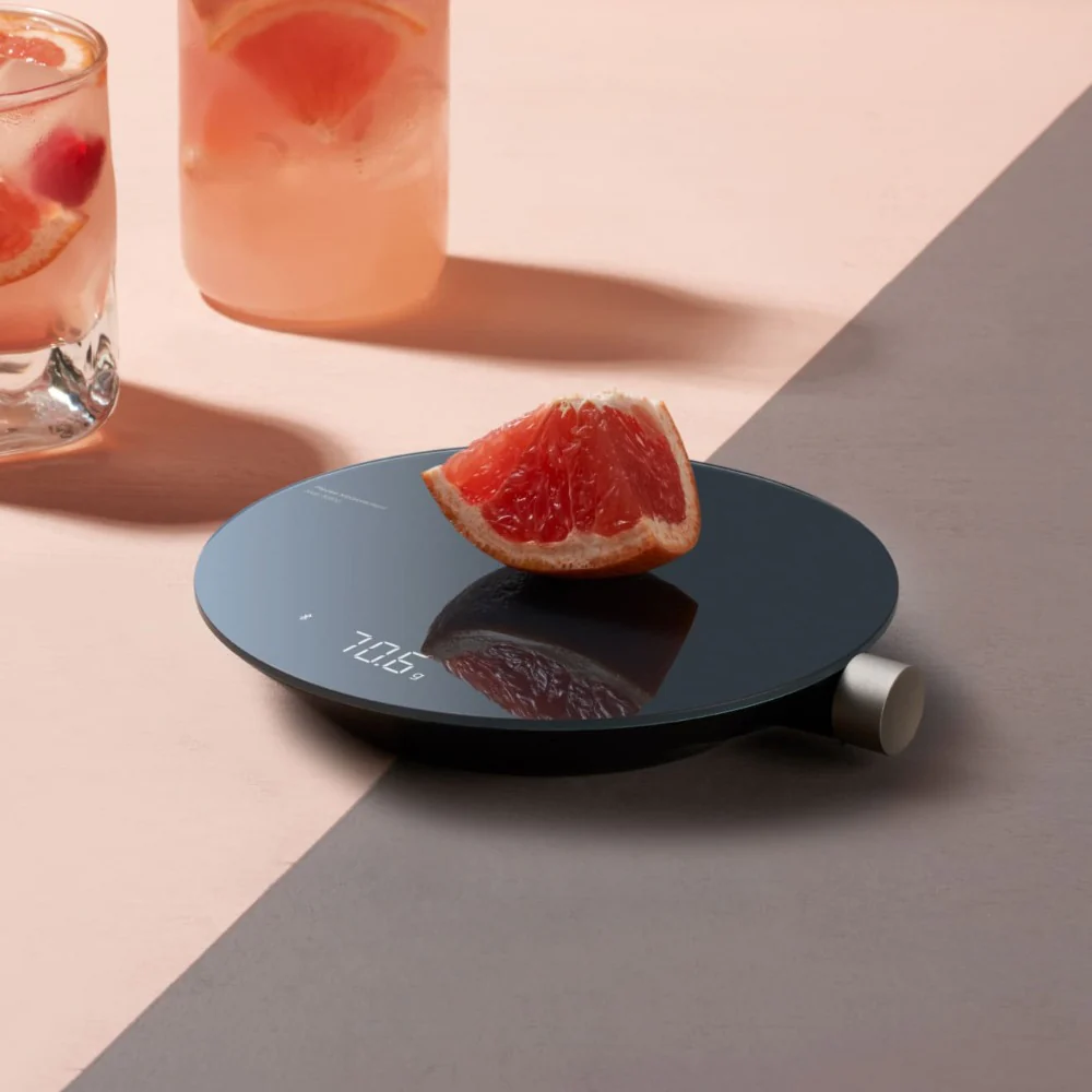 HOTO Smart Kitchen Scale, Digital kitchen scale with a grapefruit on a two-tone surface with drinks in the background