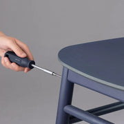 HOTO Household Tool Kit Multipurpose Set Hand using a screwdriver to adjust a blue chair against a grey background