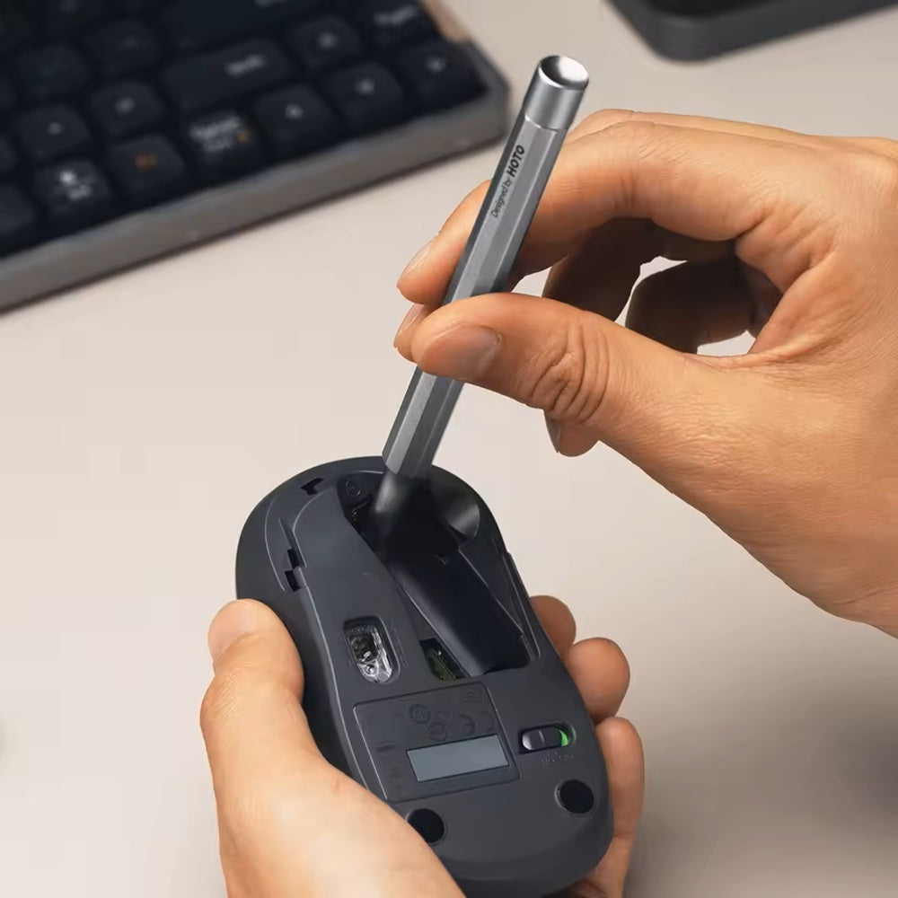 HOTO Pocket Precision Screwdriver SE Hand inserting a pen into a black electronic device on a light surface.