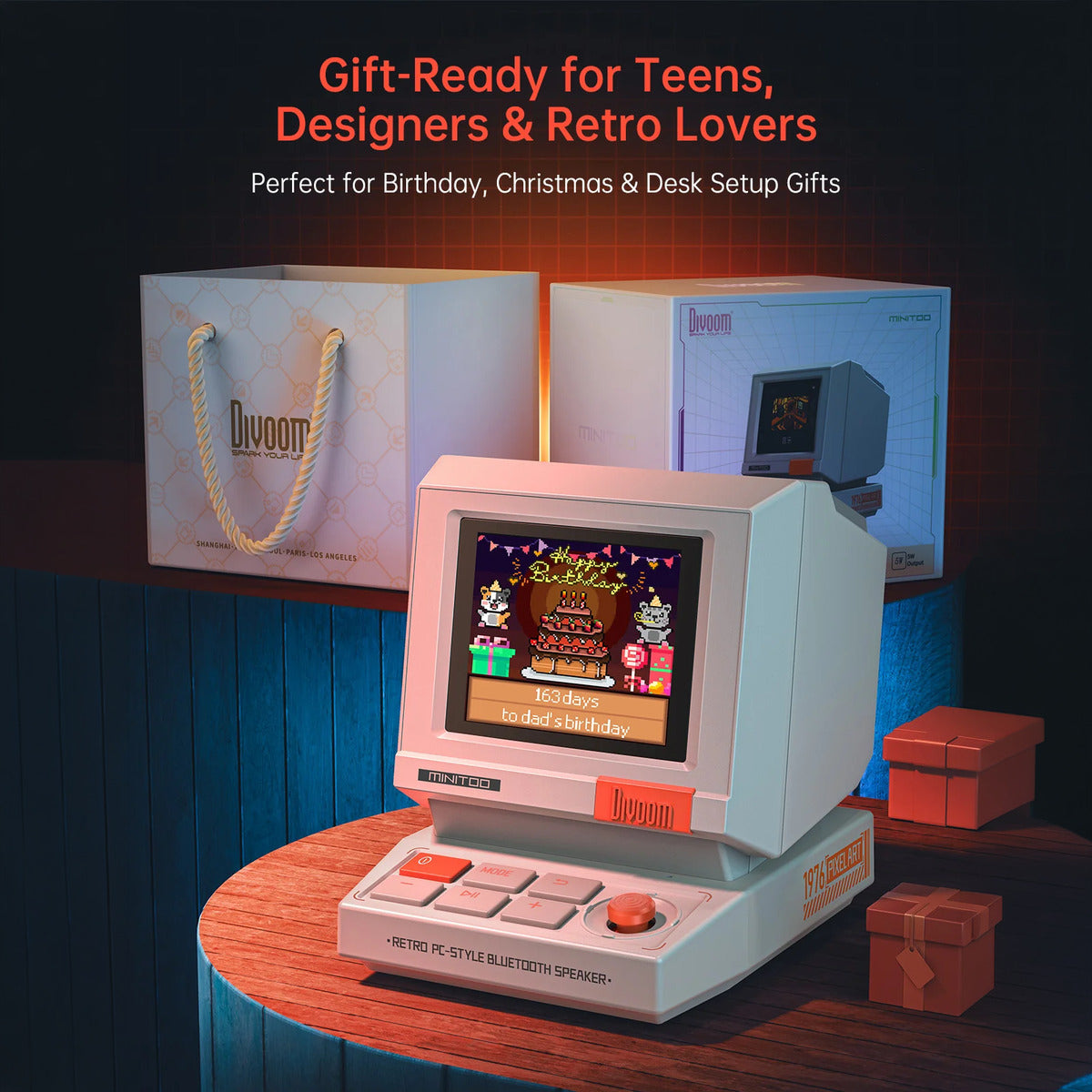 Divoom MiniToo Retro Pixel Bluetooth Speaker (1.77" Screen, 5W, App Control) Vintage-style handheld gaming console with 'Divoom' branding, surrounded by gift boxes and packaging.