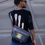 Divoom Pixoo Slingbag‑V Smart LED Sling Bag (4.7" Pixel Screen, App Control) Person wearing a black t-shirt with colorful designs and carrying a dark blue bag with digital display.