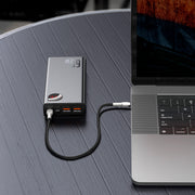 Baseus Adaman Series Laptop Power Bank 65W 20000mAh Portable power station connected to a laptop on a wooden surface