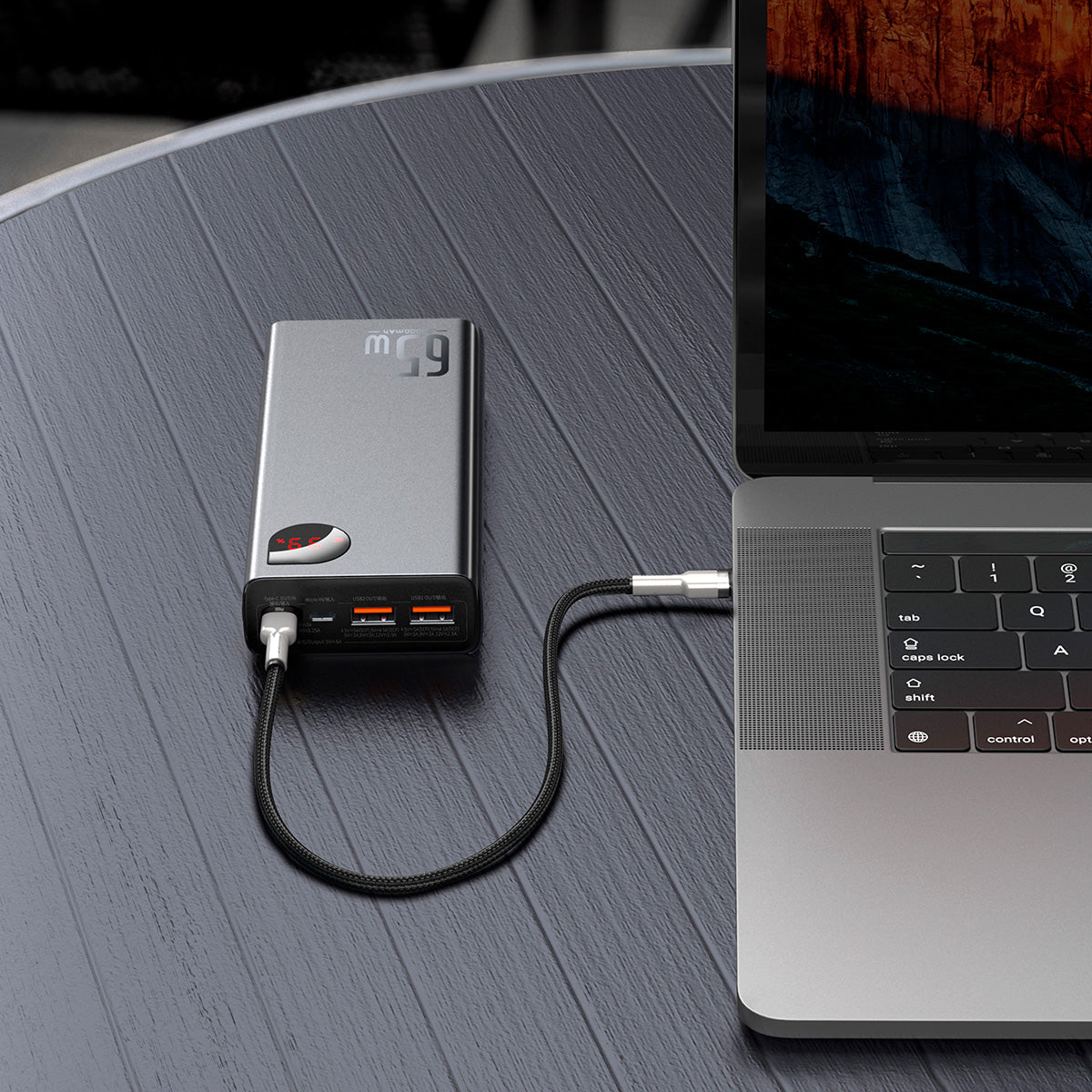 Baseus Adaman Series Laptop Power Bank 65W 20000mAh Portable power station connected to a laptop on a wooden surface