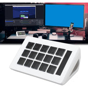 White numeric keypad with black keys in front of a computer setup with dual monitors.
