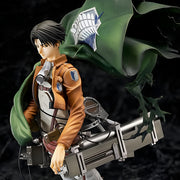 Figurine of a character from an anime or manga with a green cape and weapon on a dark background