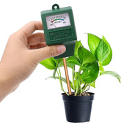 Hand holding a green moisture meter next to a potted plant on a white background