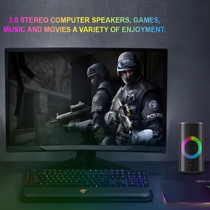 Gaming setup with monitor, keyboard, and RGB speaker on a dark surface.