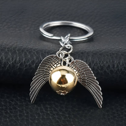 Keychain with gold ball and silver wings on a black leather surface / Harry Potter Golden Snitch Keyring