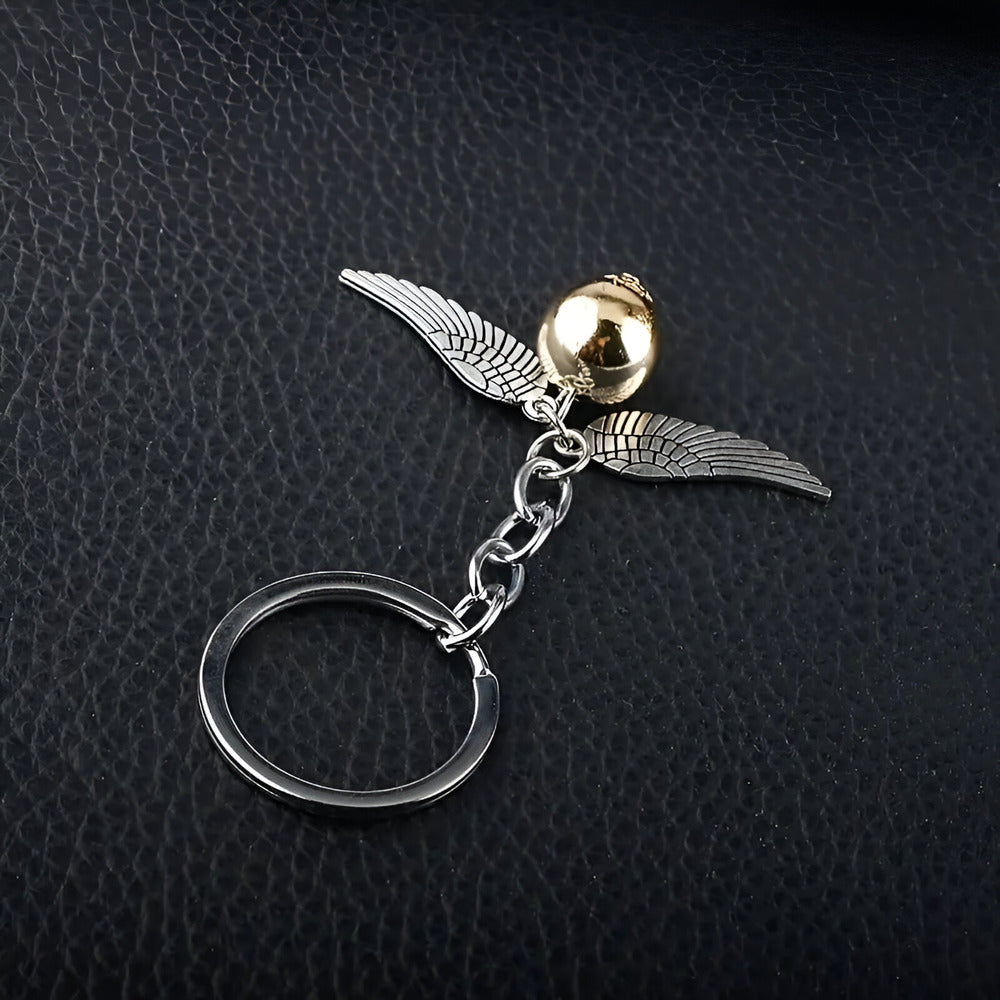 Keychain with silver wings and gold ball on a dark textured background. / Harry Potter Golden Snitch Keyring