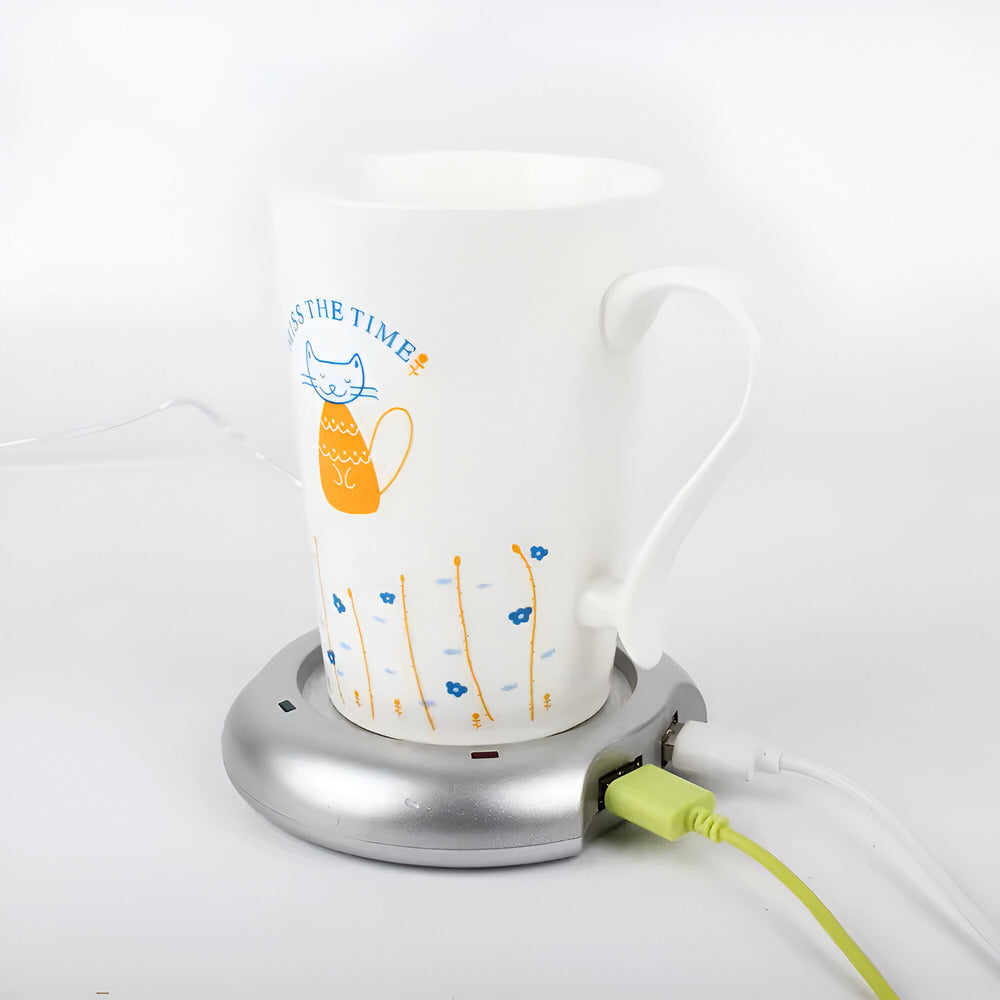 USB Mug Warmer And 4 Port Hub, White mug with a cat illustration on a silver mug warmer plugged into a white wall outlet.