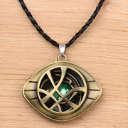 Bronze pendant with green gemstone on a black cord against a wooden / Marvels Doctor Strange - Eye of Agamotto Necklace background