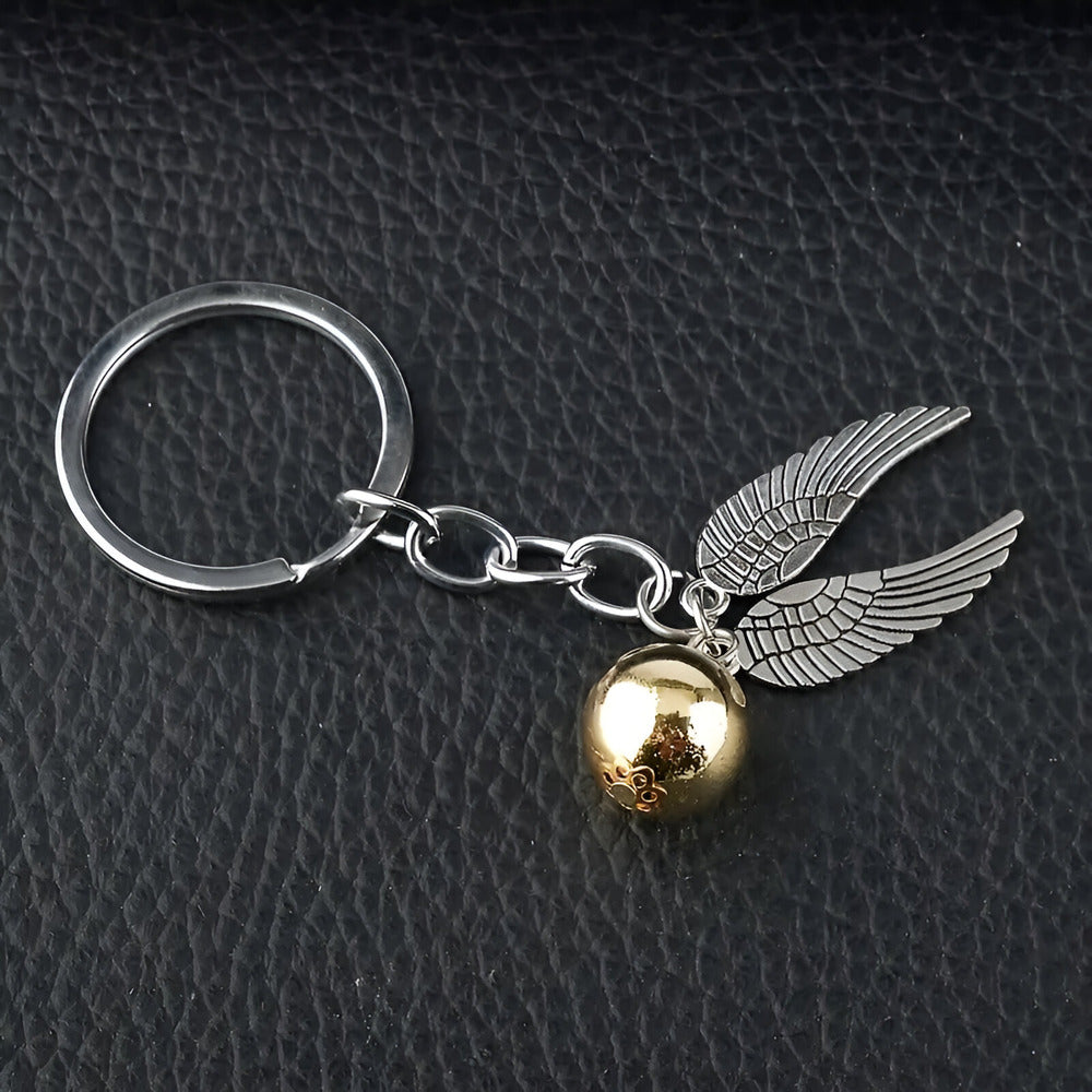 Keychain with gold ball and silver wings on a dark textured background / Harry Potter Golden Snitch Keyring
