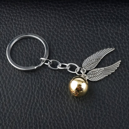 Keychain with gold ball and silver wings on a dark textured background / Harry Potter Golden Snitch Keyring
